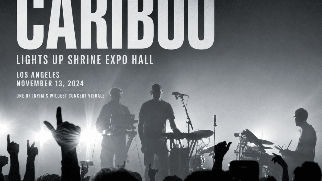 Caribou performs live at Shrine Expo Hall in Los Angeles on November 13, 2024, silhouetted against dramatic backlighting as the crowd raises their hands.