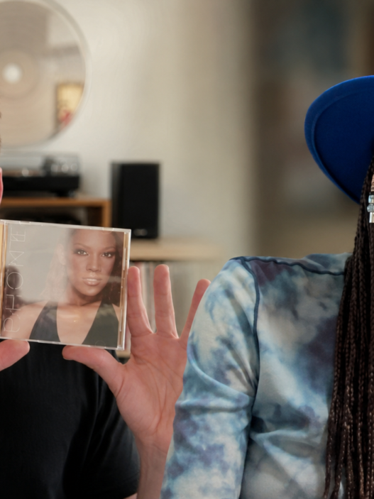Rhona Bennett smiling in a blue hat alongside a music collector holding her lost debut album on CD.