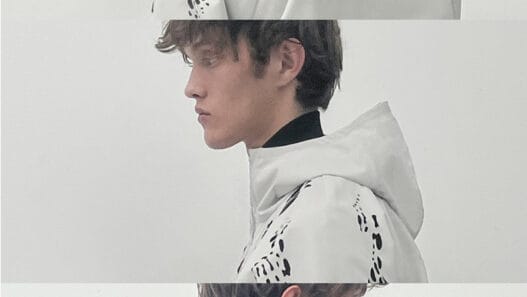 Two close portrait views of a model wearing a black HELIOT EMIL SS27 jacket with an oversized high collar and silver hardware