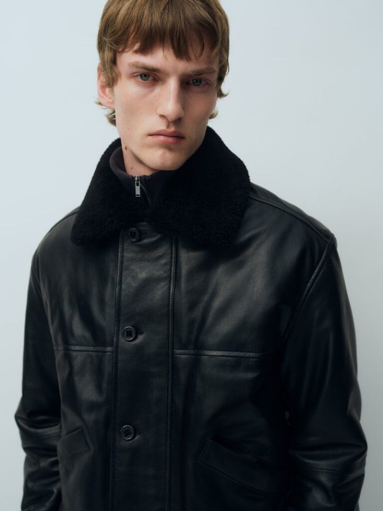 Model wears a black leather jacket with a dark shearling collar from ARKET’s Fall Winter 2026 menswear collection
