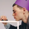 Supermodel Edzard B posing in a sculptural hat and black trousers for the Dudes fashion editorial