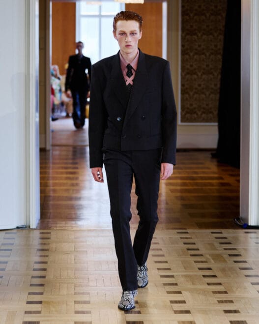 A model opens the John Lawrence Sullivan Spring/Summer 2027 runway at Berlin Fashion Week in a sharp black look.