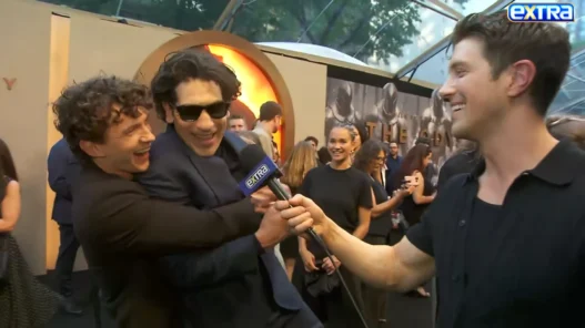 Jon Bernthal smiling beside Tom Holland during their red-carpet interview at The Odyssey premiere