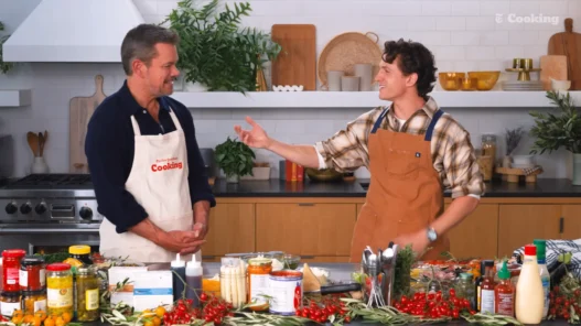 Matt Damon and Tom Holland standing at the NYT Cooking kitchen counter before making pizza
