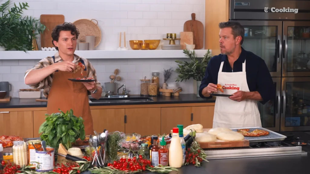 Tom Holland and Matt Damon sharing the final pizza moment in the NYT Cooking studio