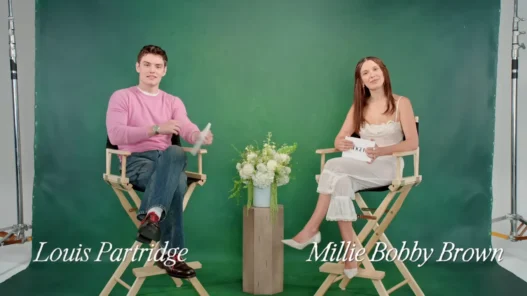 Louis Partridge and Millie Bobby Brown laugh during Vogue’s Off the Cuff rapid-fire interview.