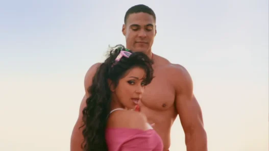 Mýa smiling in a bright yellow retro outfit in the “Give It to You” music video