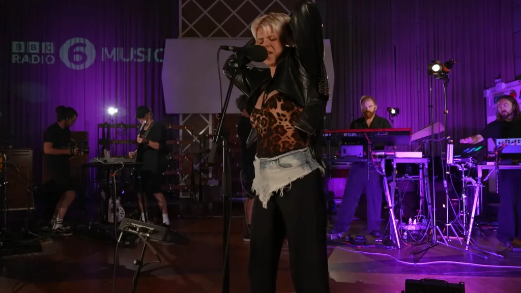 Robyn sings into a microphone during the Sucker for Love live session