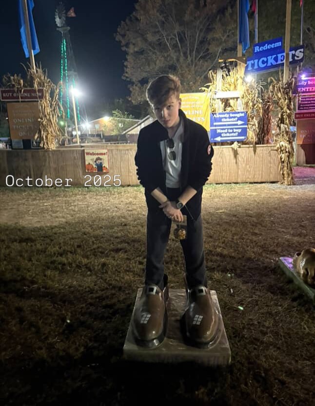 Iain Armitage standing in oversized novelty shoes at a nighttime fair in October 2025