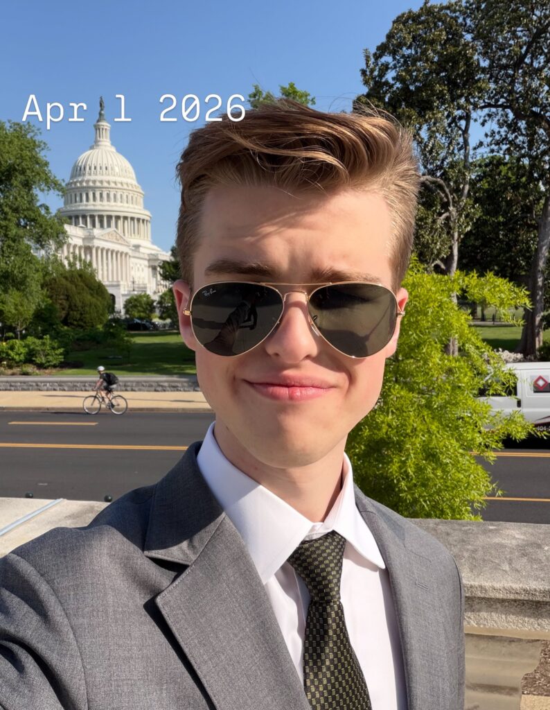 Iain Armitage wearing a suit and sunglasses in front of the U.S. Capitol in April 2026