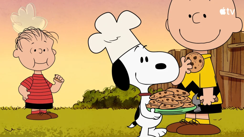 Snoopy wearing a chef hat and holding a tray of cookies beside Charlie Brown and Pig-Pen