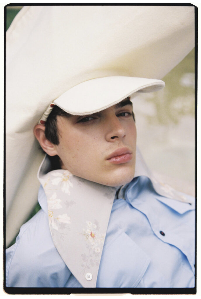 Close portrait of Ruslan in a pale blue shirt and oversized cream sculptural hat