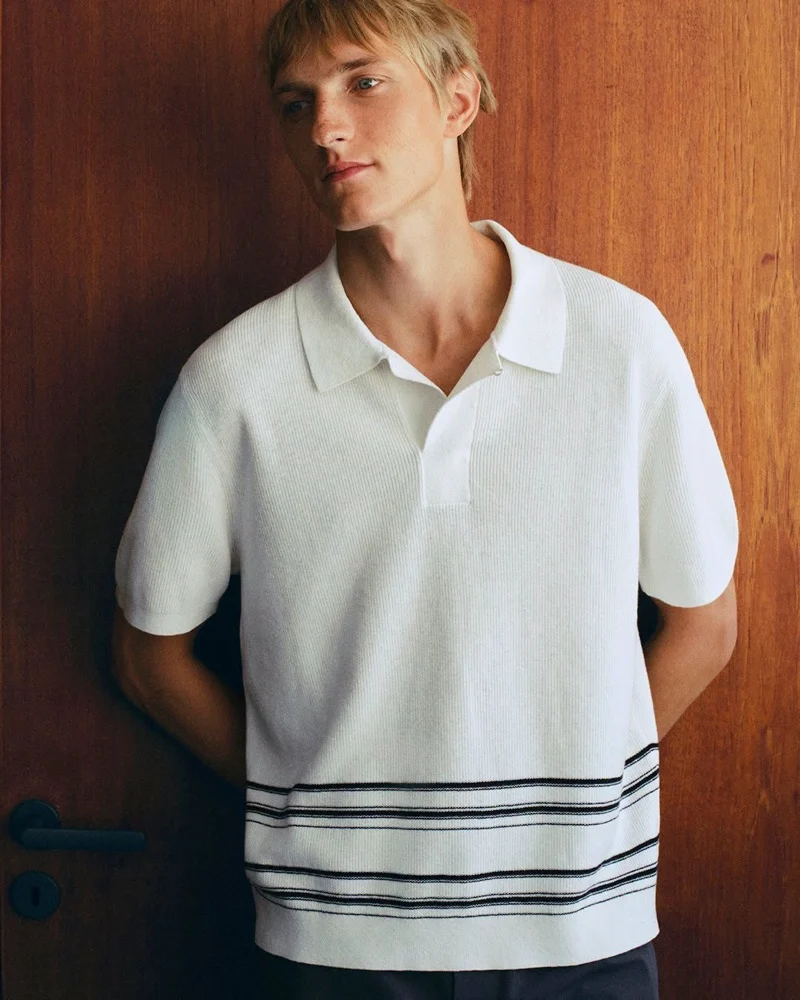 Pierrick Grégoire wearing a white textured polo with dark horizontal stripes for COS Summer 2026
