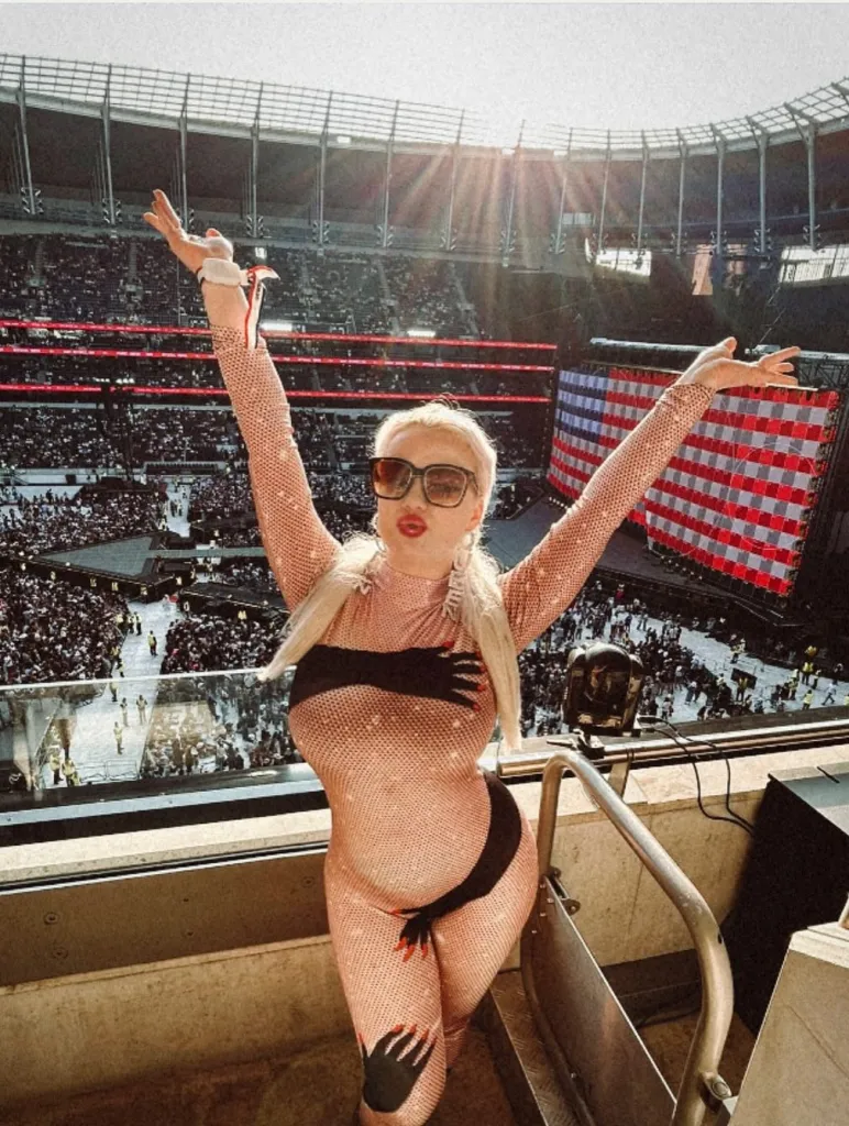 Bea MonaLisa raising both arms inside a stadium while wearing a sheer crystal-covered stage look