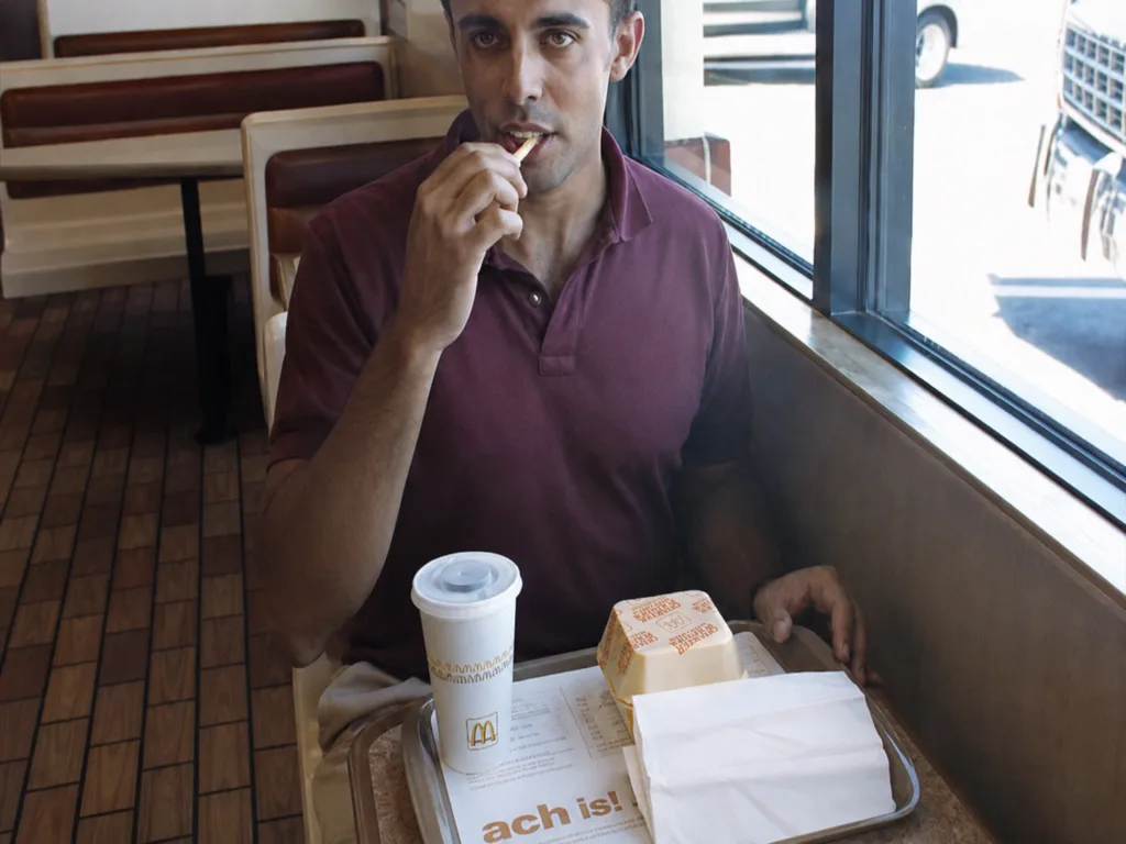 A customer eats a french fry at a McDonald’s table in 1990