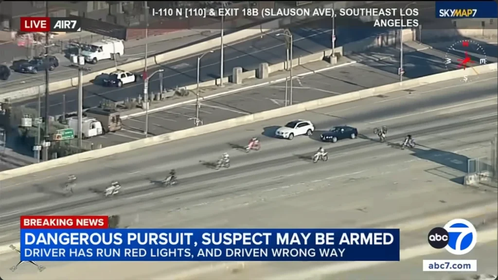 Motorcyclist performs a wheelie alongside a fleeing Mercedes-Benz during an Los Angeles police pursuit