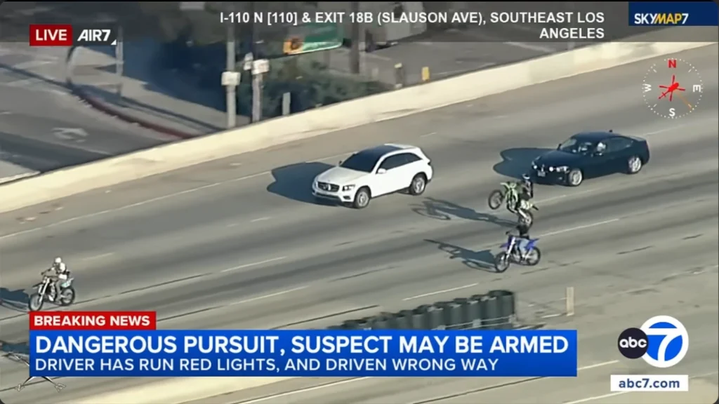 Biker rides closely beside a Mercedes-Benz pursued by LAPD on the Harbor Freeway