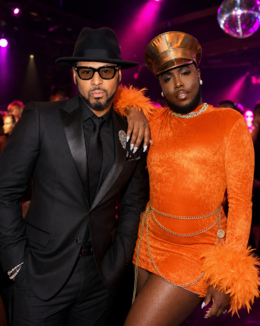 Luenell and Al B. Sure pose together at a glamorous nightclub with purple and pink lighting