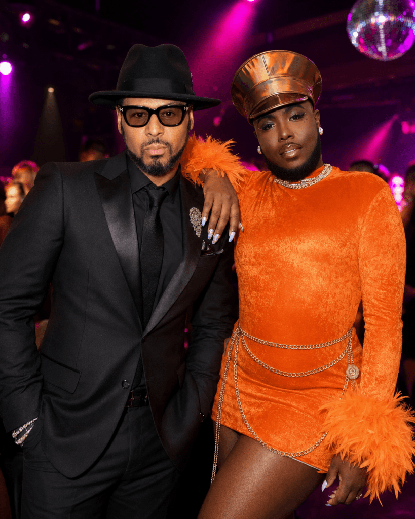Luenell and Al B. Sure pose together at a glamorous nightclub with purple and pink lighting