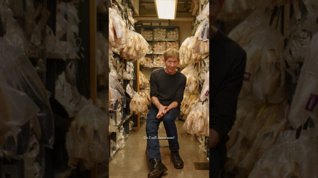 Tim Foster sits inside the New York City Ballet shoe room surrounded by rows of pointe shoes