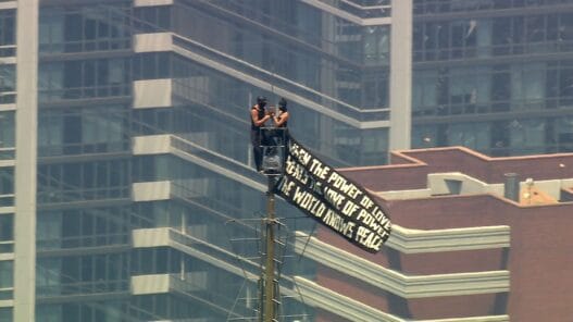 Two climbers appear near the top of the Empire State Building spire during a high-profile banner and proposal stunt in New York City.