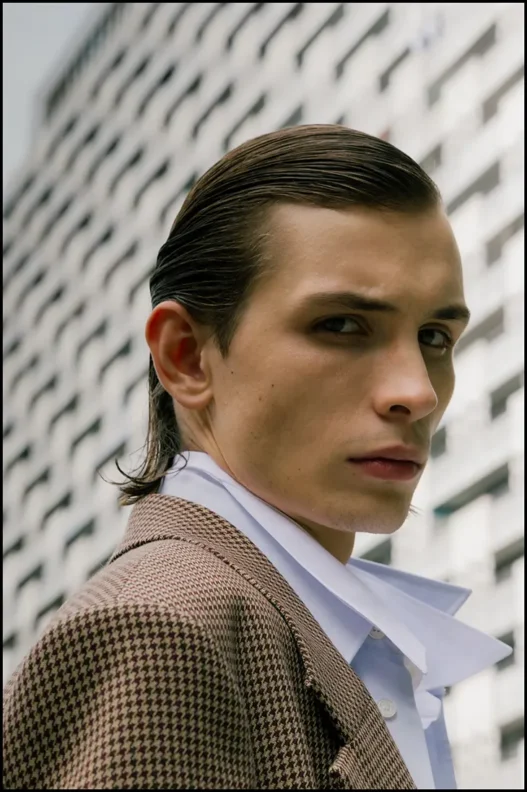 Close portrait of Anton Kügler in a checked Acne Studios coat and white shirt outdoors