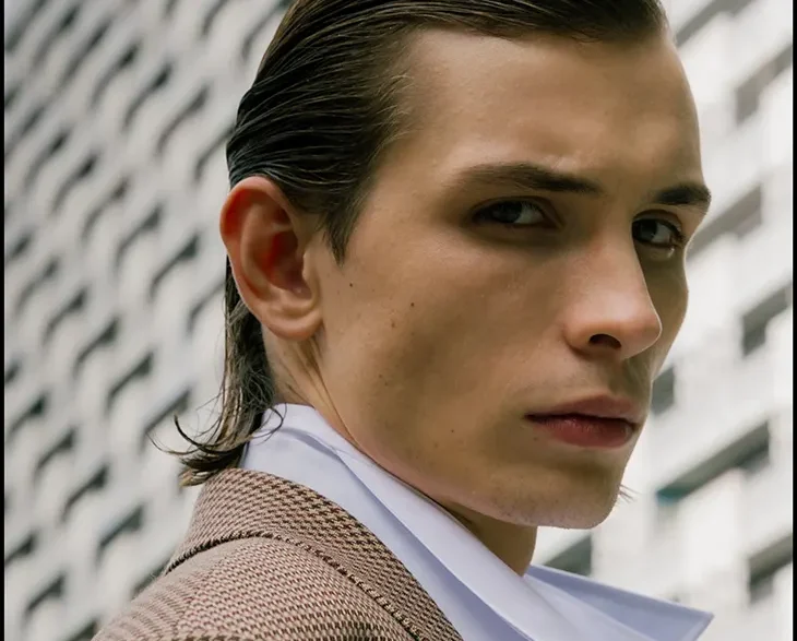 Close portrait of Anton Kügler in a checked Acne Studios coat and white shirt outdoors