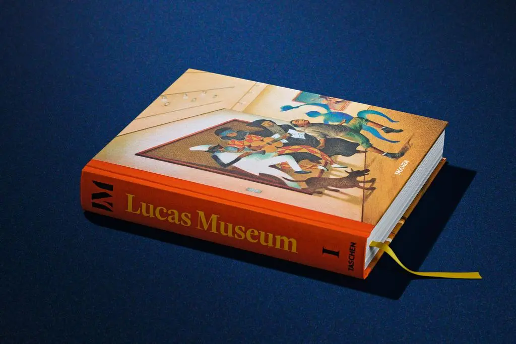 Closed first volume of the Lucas Museum of Narrative Art TASCHEN publication resting on a dark blue surface.