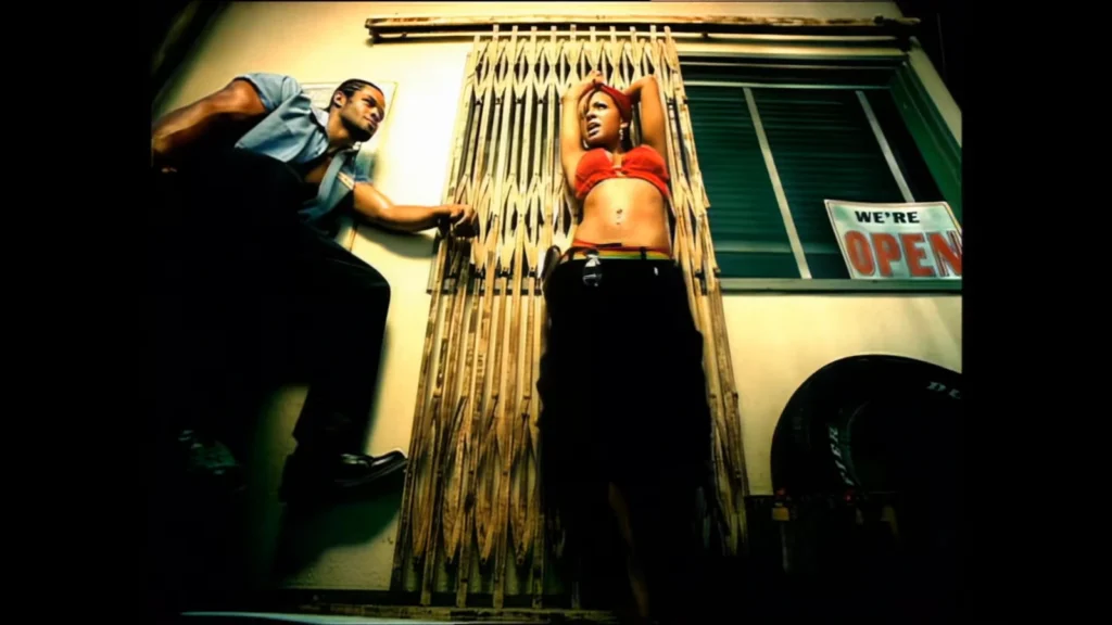 Christina Milian raises her arms beside a garage gate in the “Whatever U Want” music video.