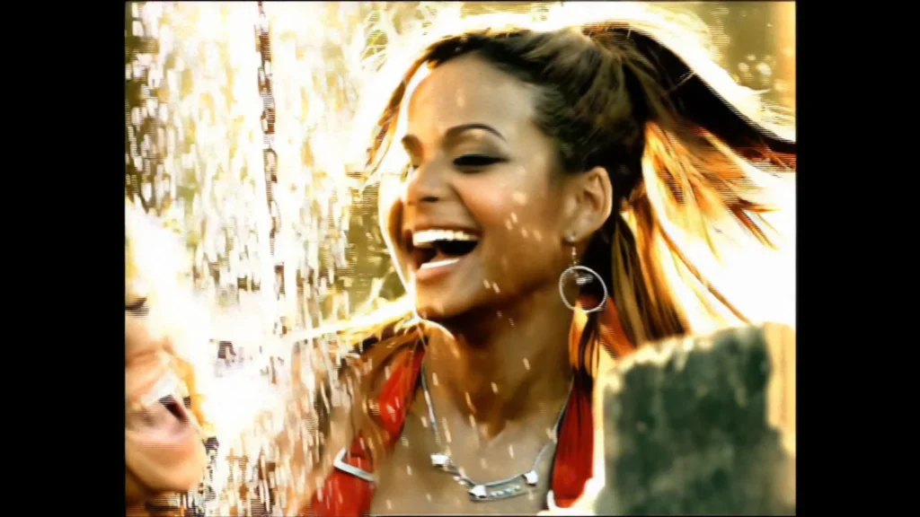 Christina Milian smiles as water sprays around her in the “Whatever U Want” music video.