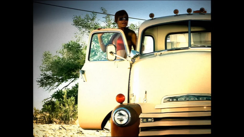 Christina Milian stands beside the open door of a white Chevrolet truck in the “Whatever U Want” music video.