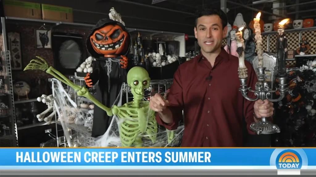 Jesse Kirsch holding a Halloween candelabra beside skeleton and pumpkin decorations