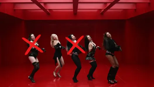 KATSEYE members in the Animal music video with red X marks over two members currently on hiatus