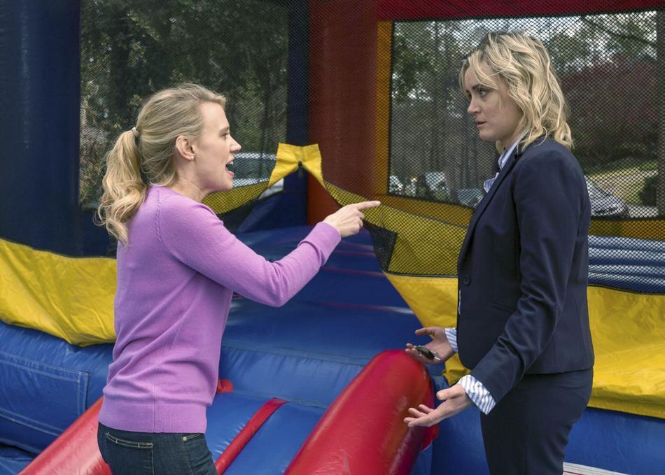 Kate McKinnon points at Taylor Schilling beside a colorful bounce house in Family