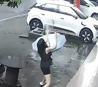 Woman using an umbrella during falling cat rescue in Guangxi, China