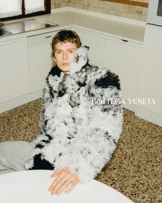 Leon Dame seated in an oversized curly shearling coat for Bottega Veneta Fall 2026