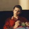 Roman Lenoir in a red shirt holding a flower for Zara’s Baisi Guadagnino campaign