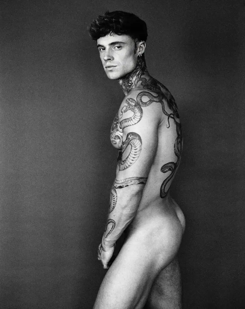 Black-and-white side portrait of Samuel Dohmen looking over his shoulder, showing his back tattoos