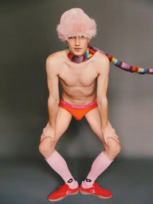 Male model Konrad Rech posing shirtless in white briefs with a large feathered hat for Arthur Iskandarov's FLÂNEUR editorial