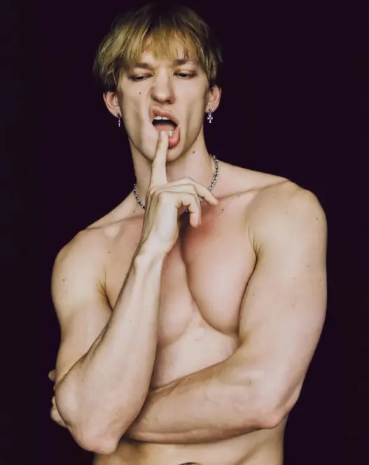 Shirtless blond model Andrii Levchenko posing with a finger against his lips in a portrait photographed by Ferran Casanova