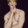 Shirtless blond model Andrii Levchenko posing with a finger against his lips in a portrait photographed by Ferran Casanova