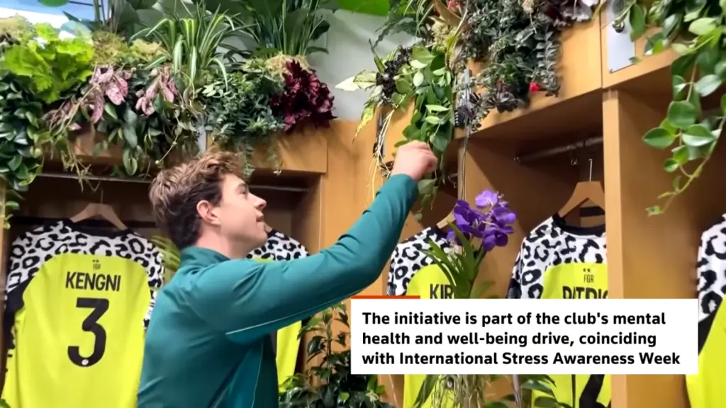 Forest Green Rovers player examines greenery beside the lockers