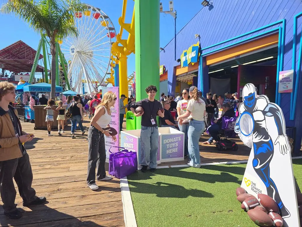 Isaac Ordonez on the Santa Monica Pier boardwalk near the Giveback Quarterback game and event volunteers