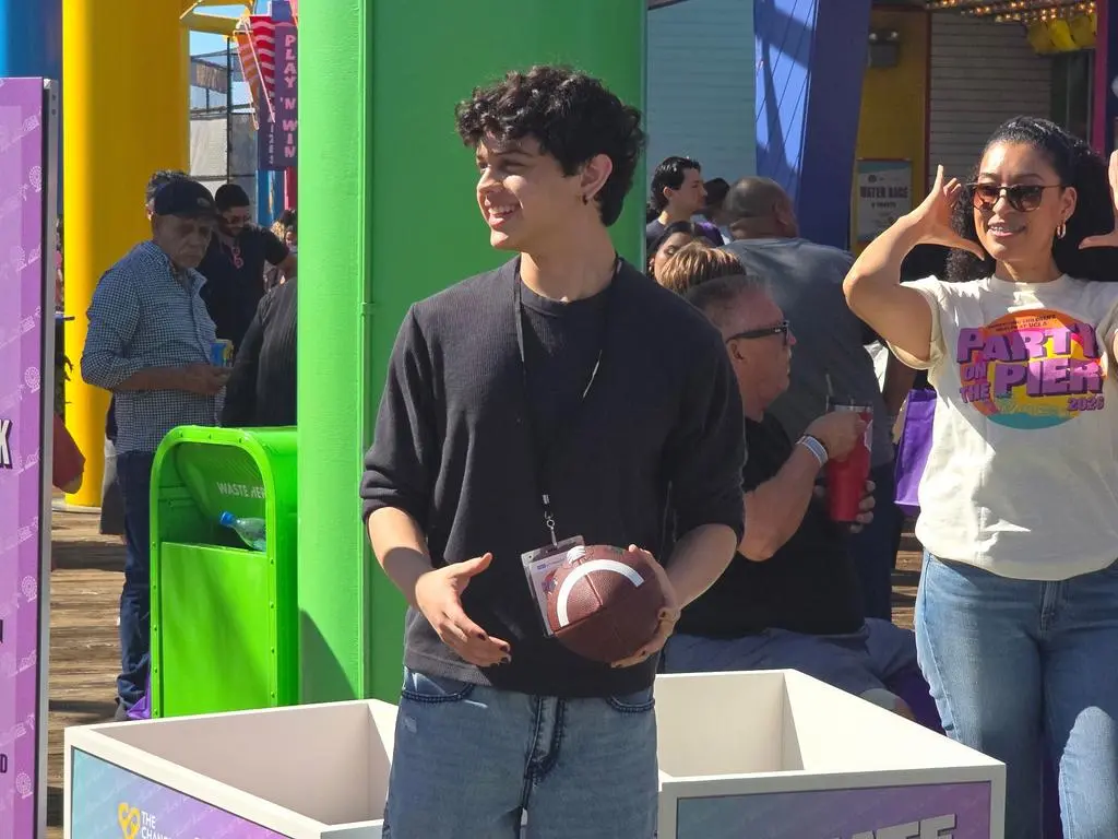 Isaac Ordonez with volunteers at the Giveback Quarterback football booth at Pacific Park