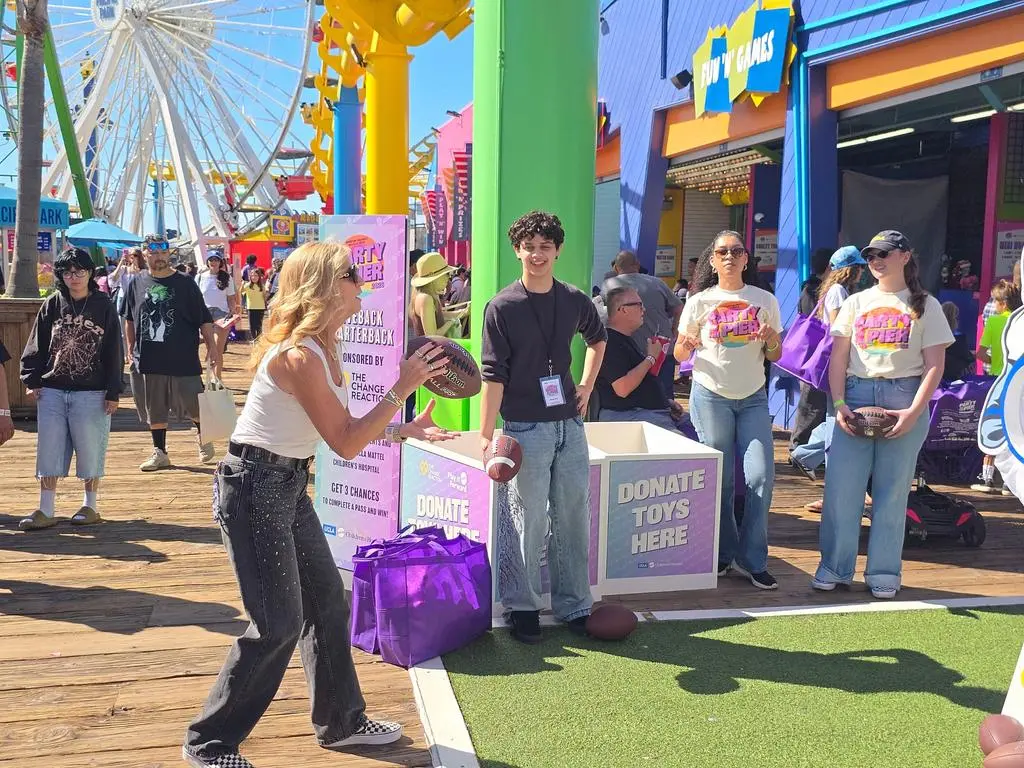 A guest holding a football near Isaac Ordonez at Party on the Pier