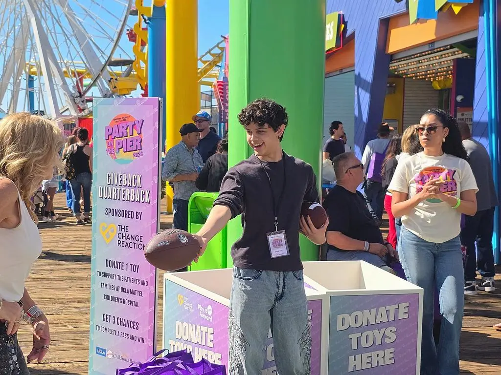 Isaac Ordonez offering a football to a guest at the boardwalk fundraising game