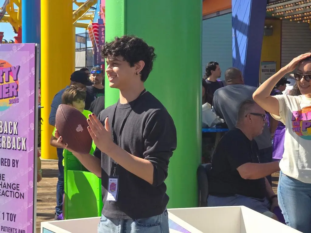 Smiling Isaac Ordonez holding a football at UCLA Party on the Pier 2026