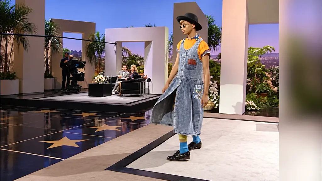 Young model walking the set in a denim jumper dress at the Pee-wee Herman fashion presentation