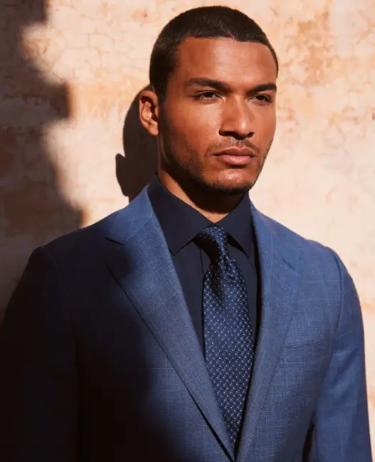 Model Paulo Lopes Lucio wearing a tailored blue suit, navy shirt and patterned tie in Peter Jackson Australia's Destination: Summer 2026 campaign, photographed by Alfi Gomez.