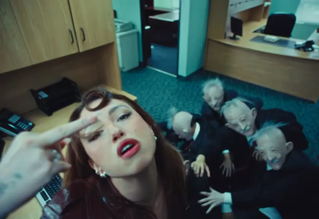 Rêve looking upward as several suited record executive characters reach toward her in Church of Sound video